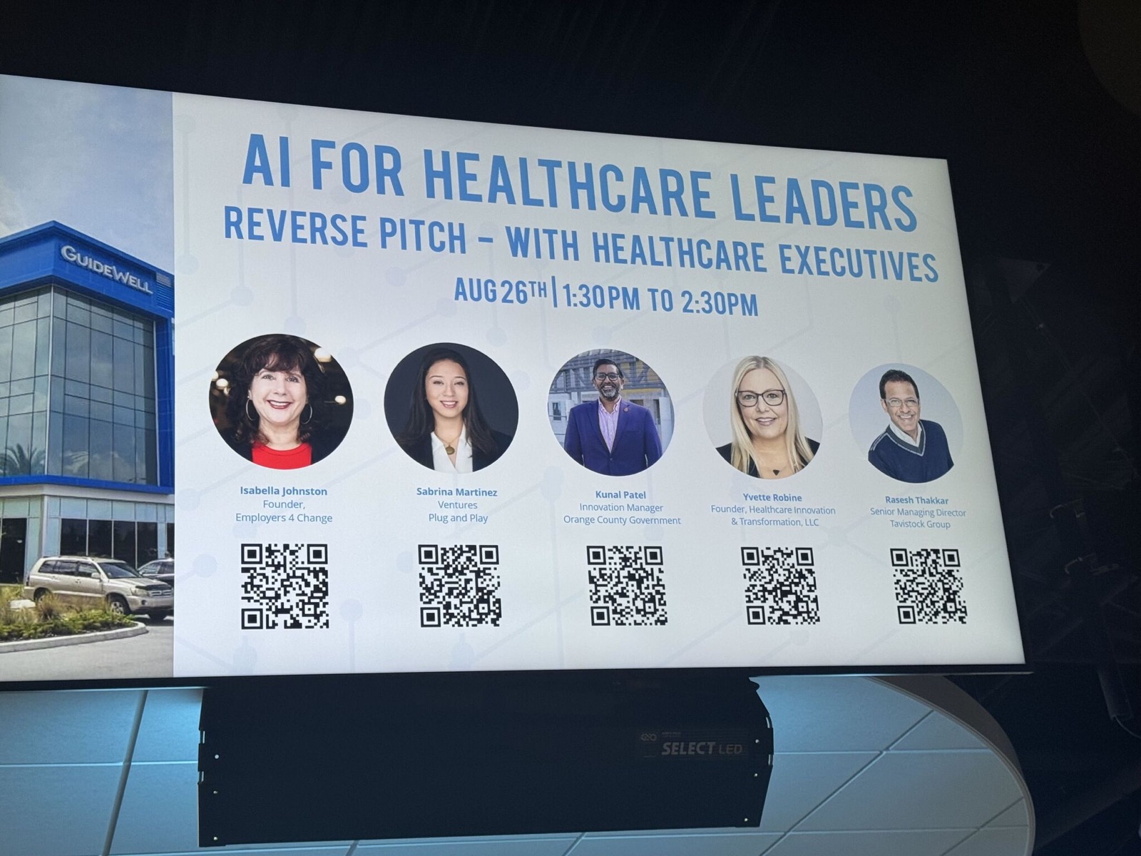 Event screen at the GuideWell Innovation Center announcing "AI for Healthcare Leaders — Reverse Pitch with Healthcare Executives", August 26, 1:30 to 2:30 PM, with headshots of the five panelists.